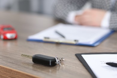 Photo of Buying auto. Car key on wooden table, selective focus