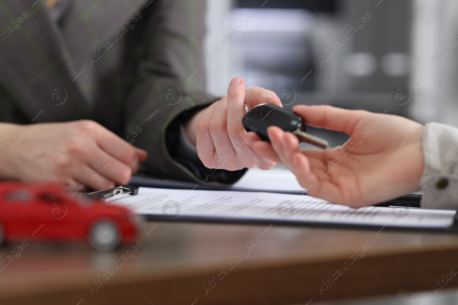 Photo of Buying auto. Client getting car key at table, closeup