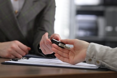 Photo of Buying auto. Client getting car key at table, closeup