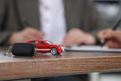 Photo of Car model and key on wooden table, selective focus. Buying auto