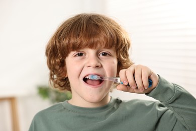 Photo of Cute boy brushing his teeth at home