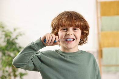 Cute boy brushing his teeth at home