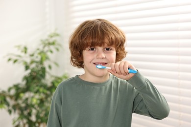 Cute boy brushing his teeth at home