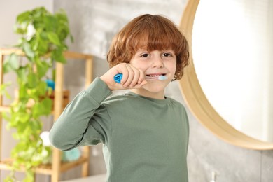 Cute boy brushing his teeth at home