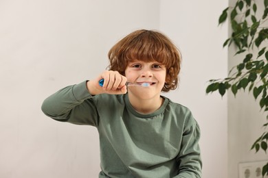 Cute boy brushing his teeth at home