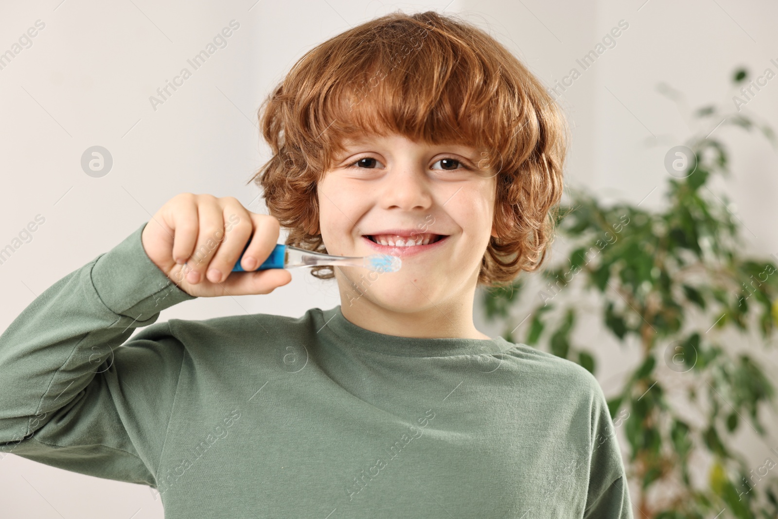 Photo of Cute boy brushing his teeth at home