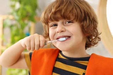 Cute boy brushing his teeth at home