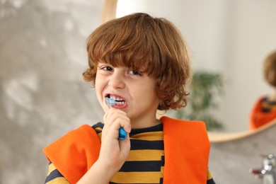 Photo of Cute boy brushing his teeth at home