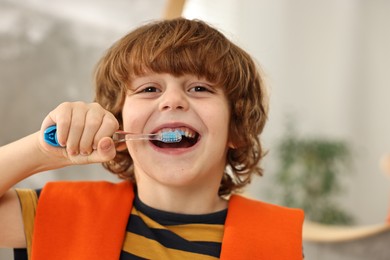 Cute boy brushing his teeth at home