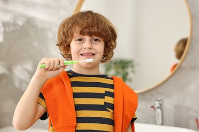 Photo of Cute boy brushing his teeth at home