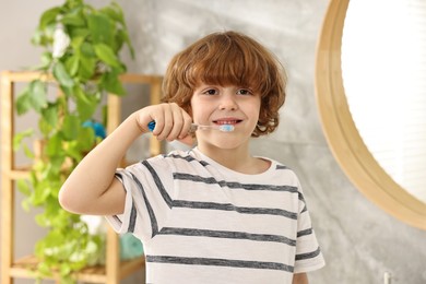 Photo of Cute boy brushing his teeth in bathroom