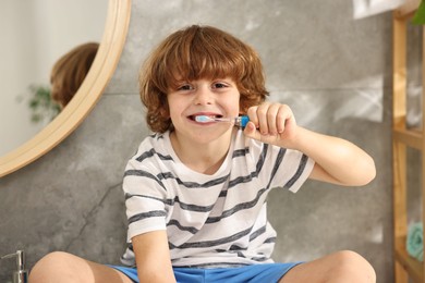 Cute boy brushing his teeth in bathroom