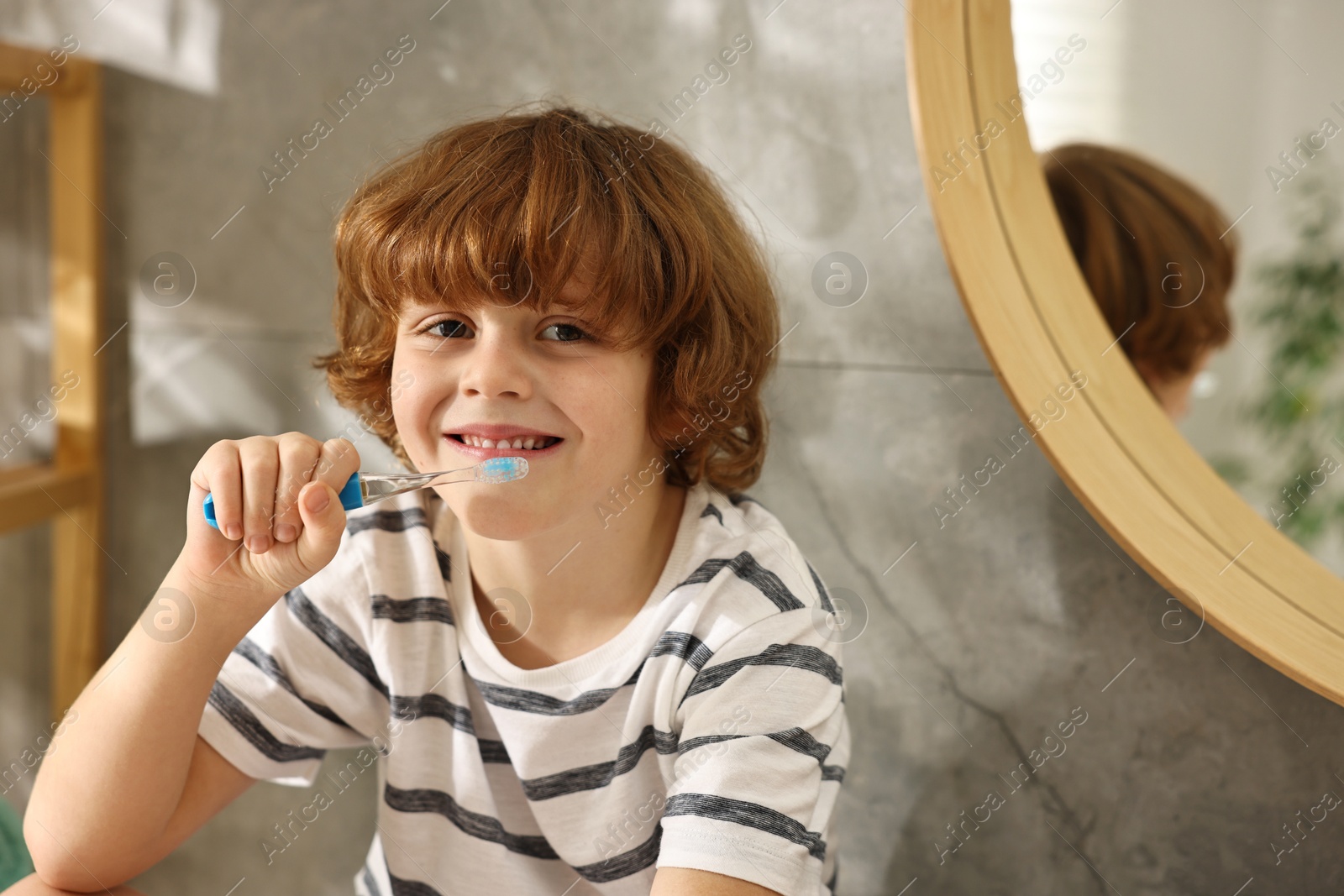 Photo of Cute boy brushing his teeth in bathroom