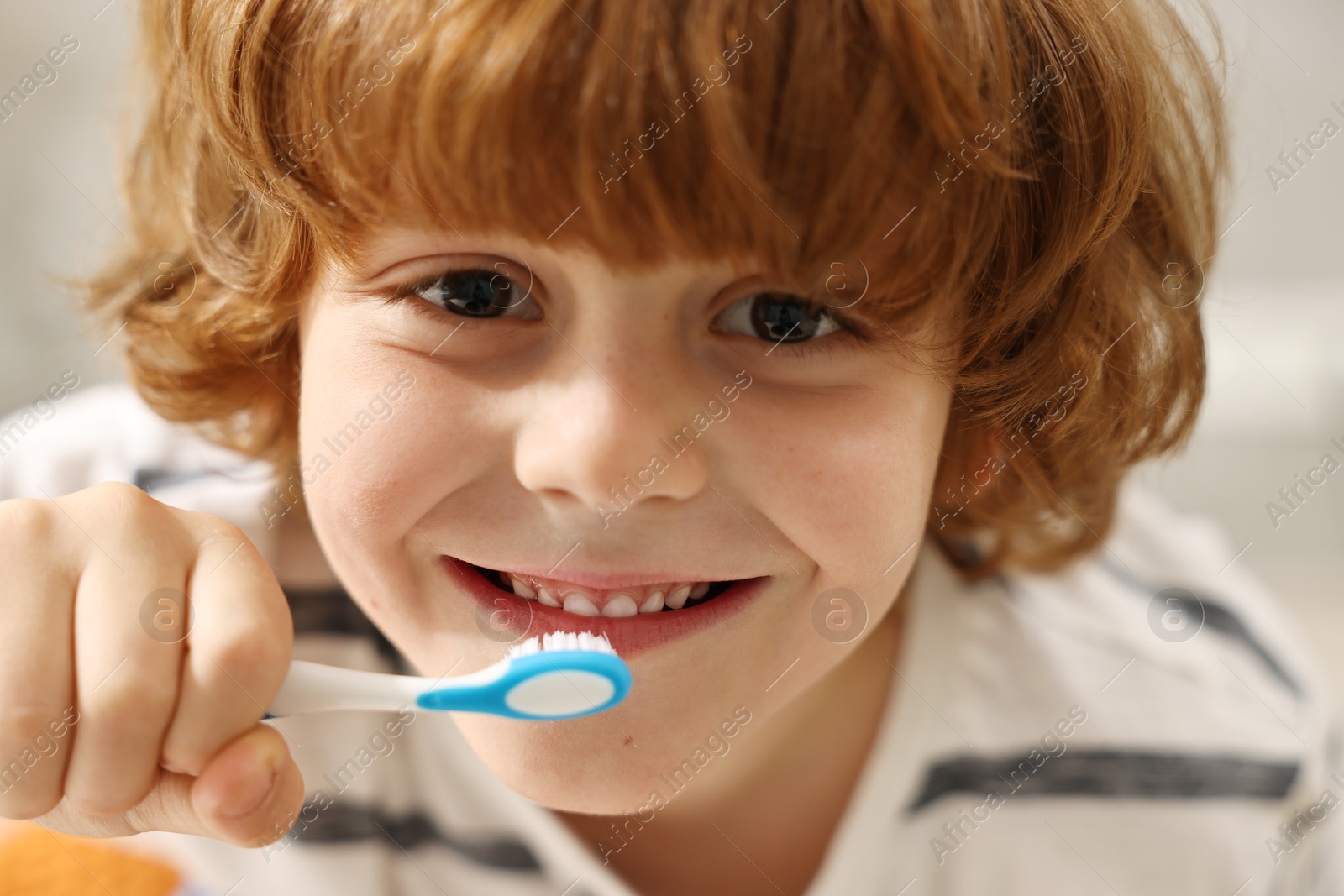 Photo of Cute boy brushing his teeth indoors, closeup