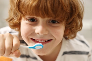 Photo of Cute boy brushing his teeth indoors, closeup