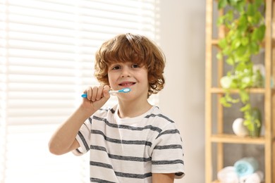 Cute boy brushing his teeth in bathroom