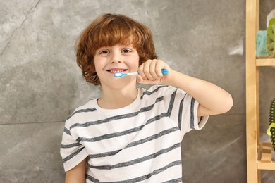 Photo of Cute boy brushing his teeth in bathroom