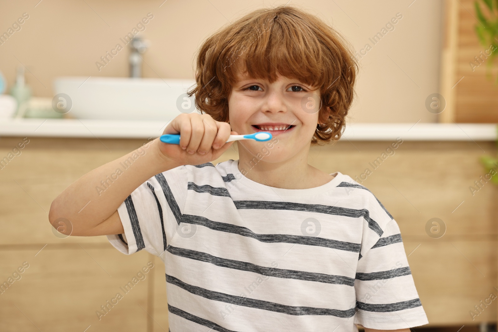 Photo of Cute boy brushing his teeth in bathroom