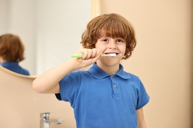 Photo of Cute boy brushing his teeth at home, selective focus