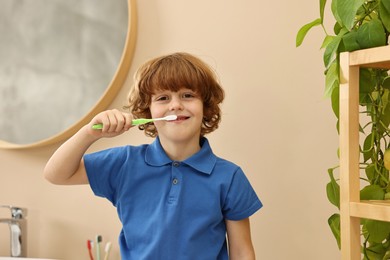 Photo of Cute boy brushing his teeth in bathroom