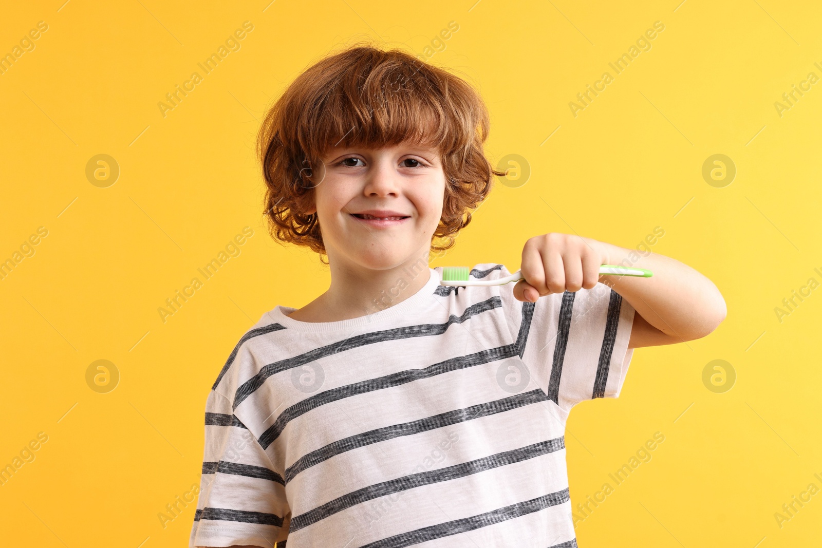 Photo of Cute boy with toothbrush on yellow background