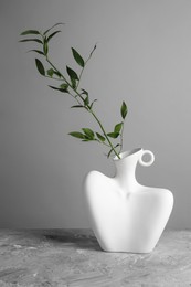 Stylish vase with green branch on grey table