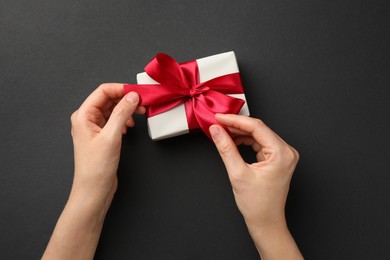 Photo of Woman opening gift box on black background, top view