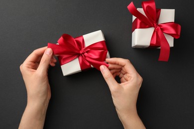 Photo of Woman opening gift box on black background, top view