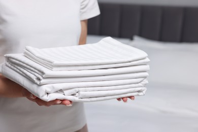 Photo of Woman with clean bed linens indoors, closeup