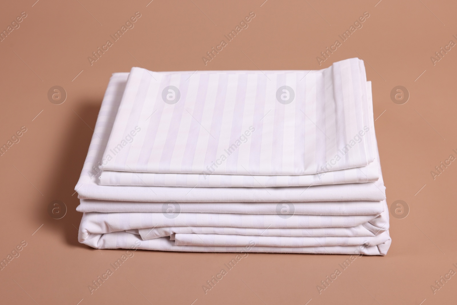 Photo of Stack of clean bed linens on beige background