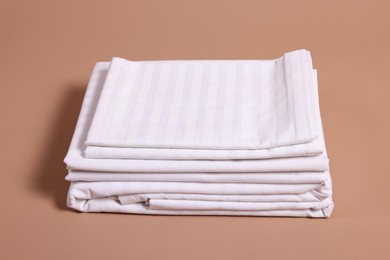 Photo of Stack of clean bed linens on beige background