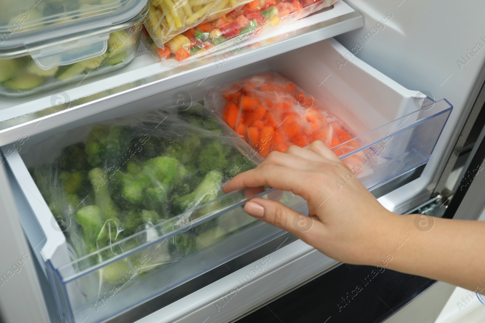 Photo of Woman taking frozen vegetables from refrigerator, closeup