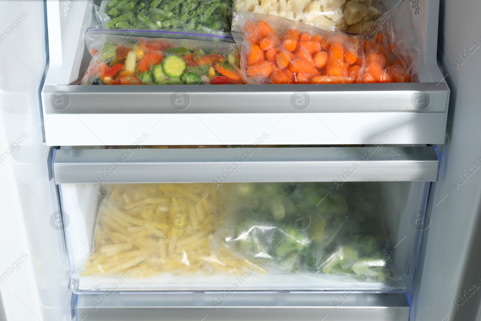 Photo of Plastic bags with different frozen vegetables in refrigerator