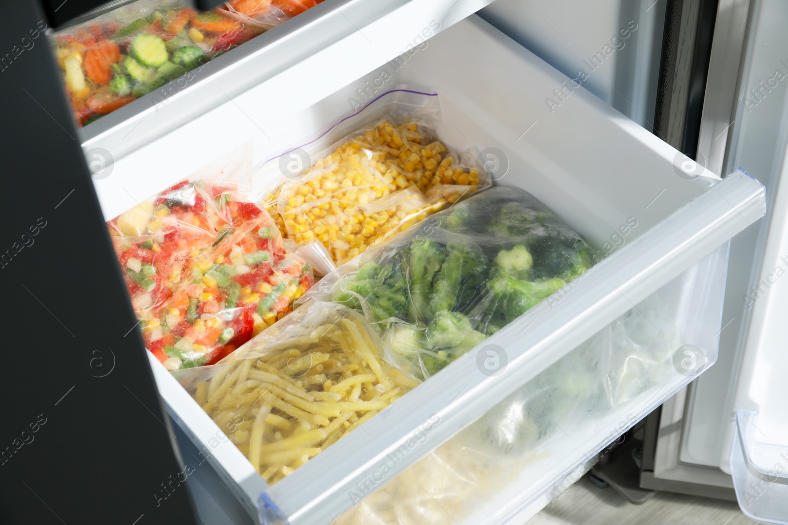 Photo of Plastic bags with different frozen vegetables in refrigerator