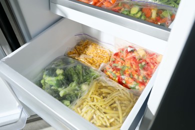 Photo of Plastic bags with different frozen vegetables in refrigerator