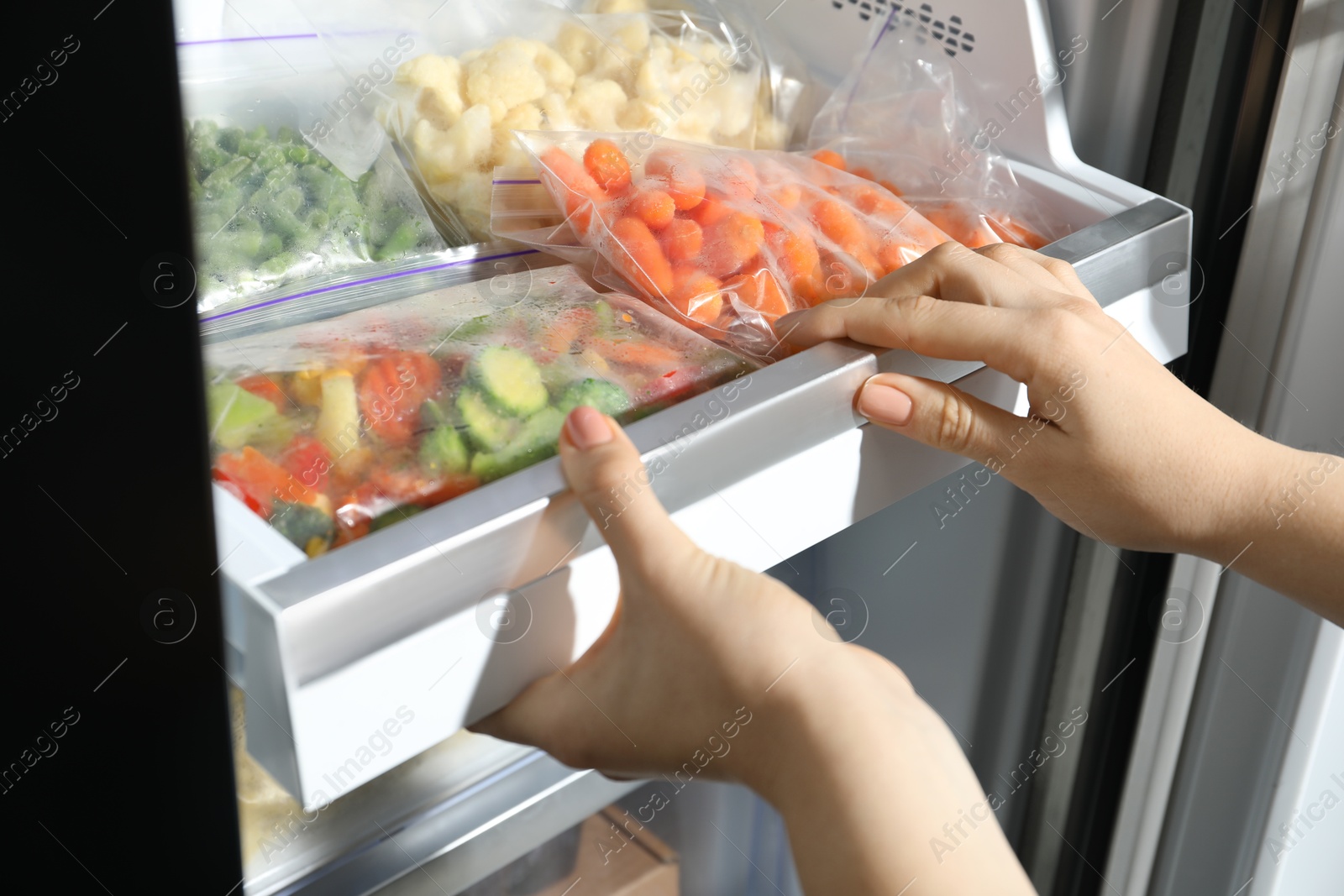 Photo of Woman taking frozen vegetables from refrigerator, closeup