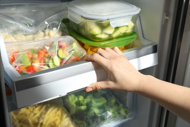 Photo of Woman taking frozen vegetables from refrigerator, closeup