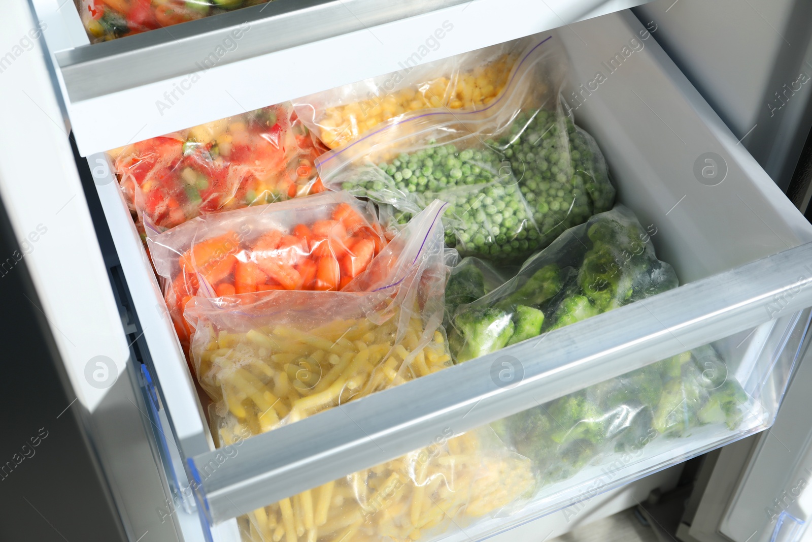 Photo of Plastic bags with different frozen vegetables in refrigerator