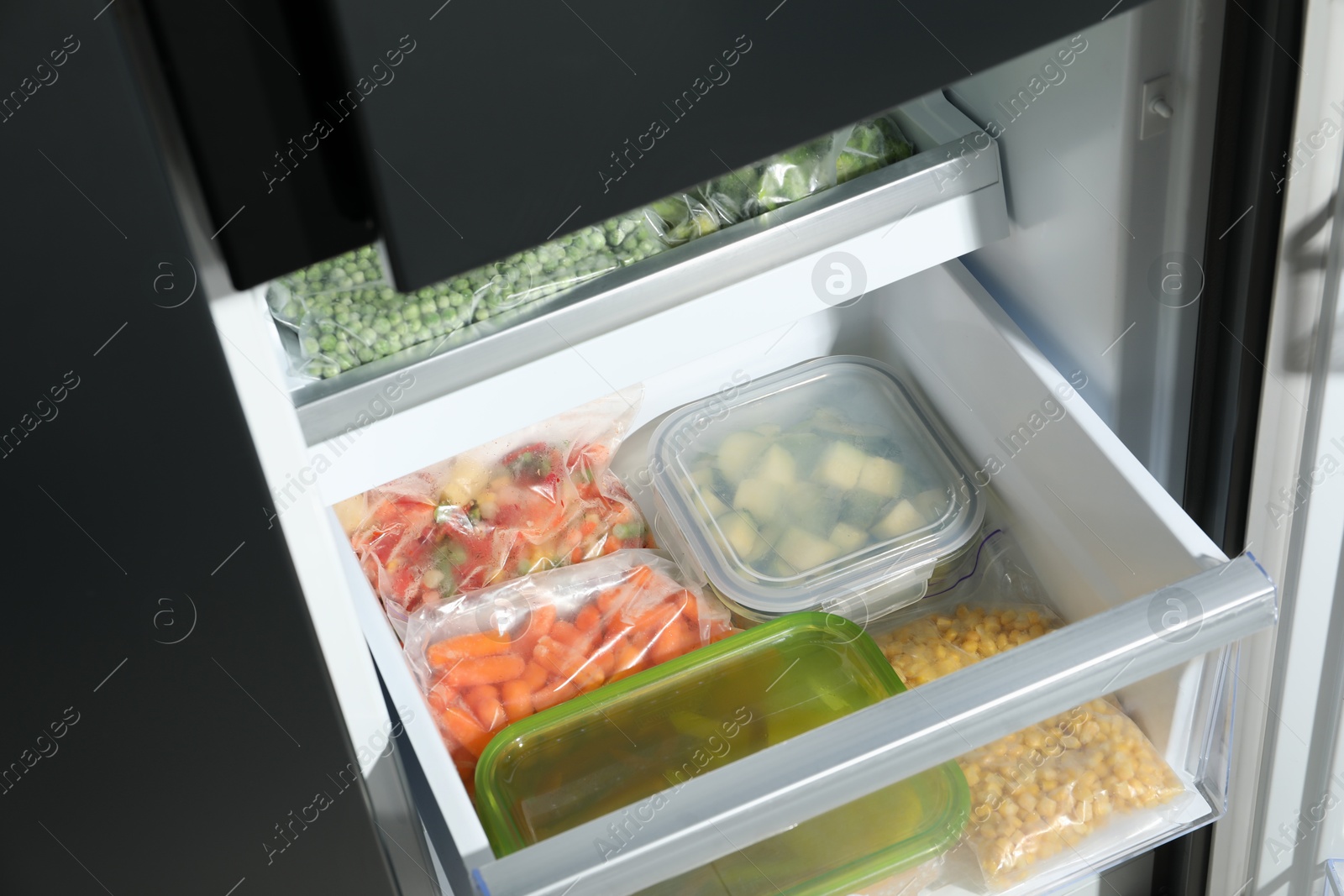 Photo of Plastic bags and glass containers with different frozen vegetables in refrigerator