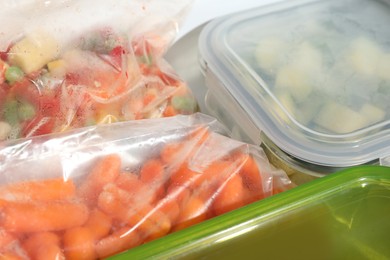 Photo of Plastic bags and glass container with different frozen vegetables in refrigerator, closeup