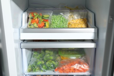 Photo of Plastic bags with different frozen vegetables in refrigerator