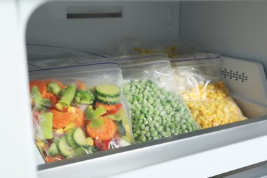 Photo of Plastic bags with different frozen vegetables in refrigerator, closeup