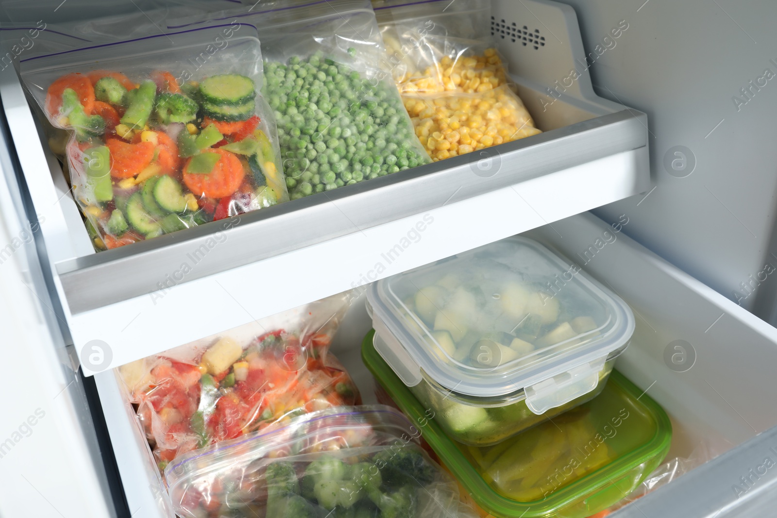 Photo of Plastic bags and glass containers with different frozen vegetables in refrigerator