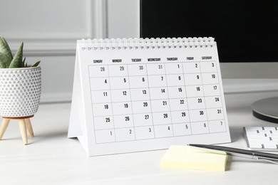 Photo of Timetable. Monthly planner, floral decor, stationery and computer on white table