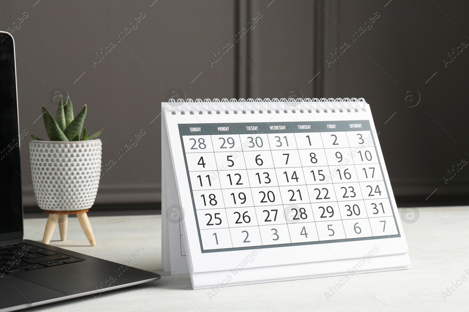 Photo of Timetable. Calendar, laptop and floral decor on white table