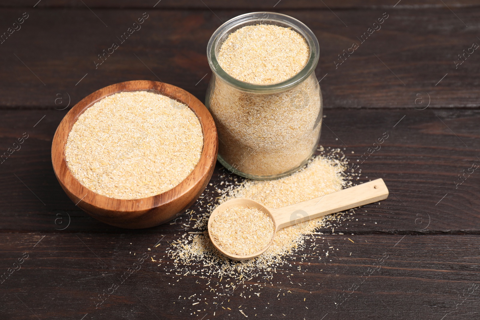 Photo of Oat bran in glass jar, bowl and spoon on wooden table