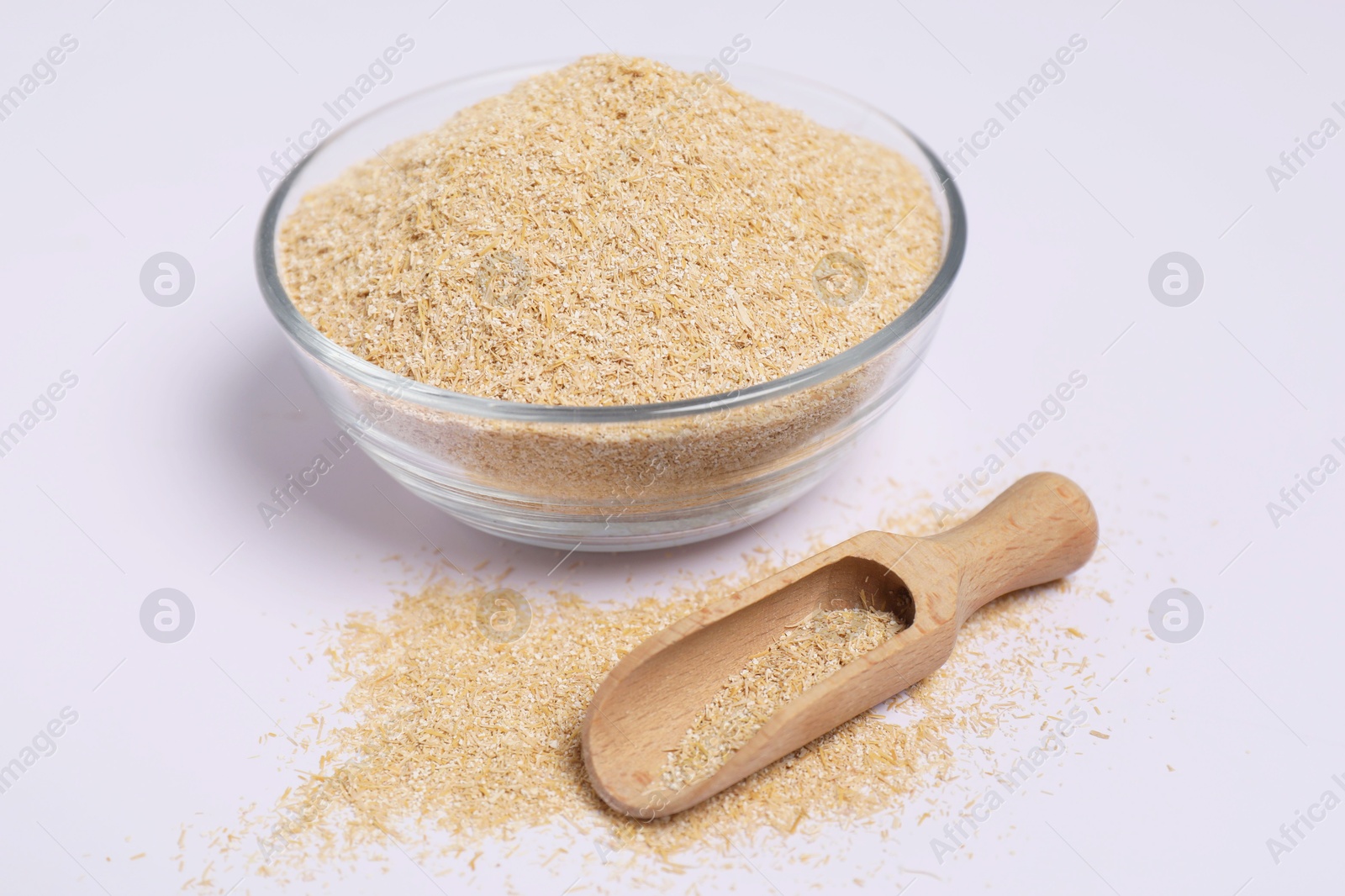 Photo of Oat bran in glass bowl and wooden scoop on white background