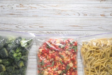 Photo of Different frozen vegetables in plastic bags on wooden table, top view