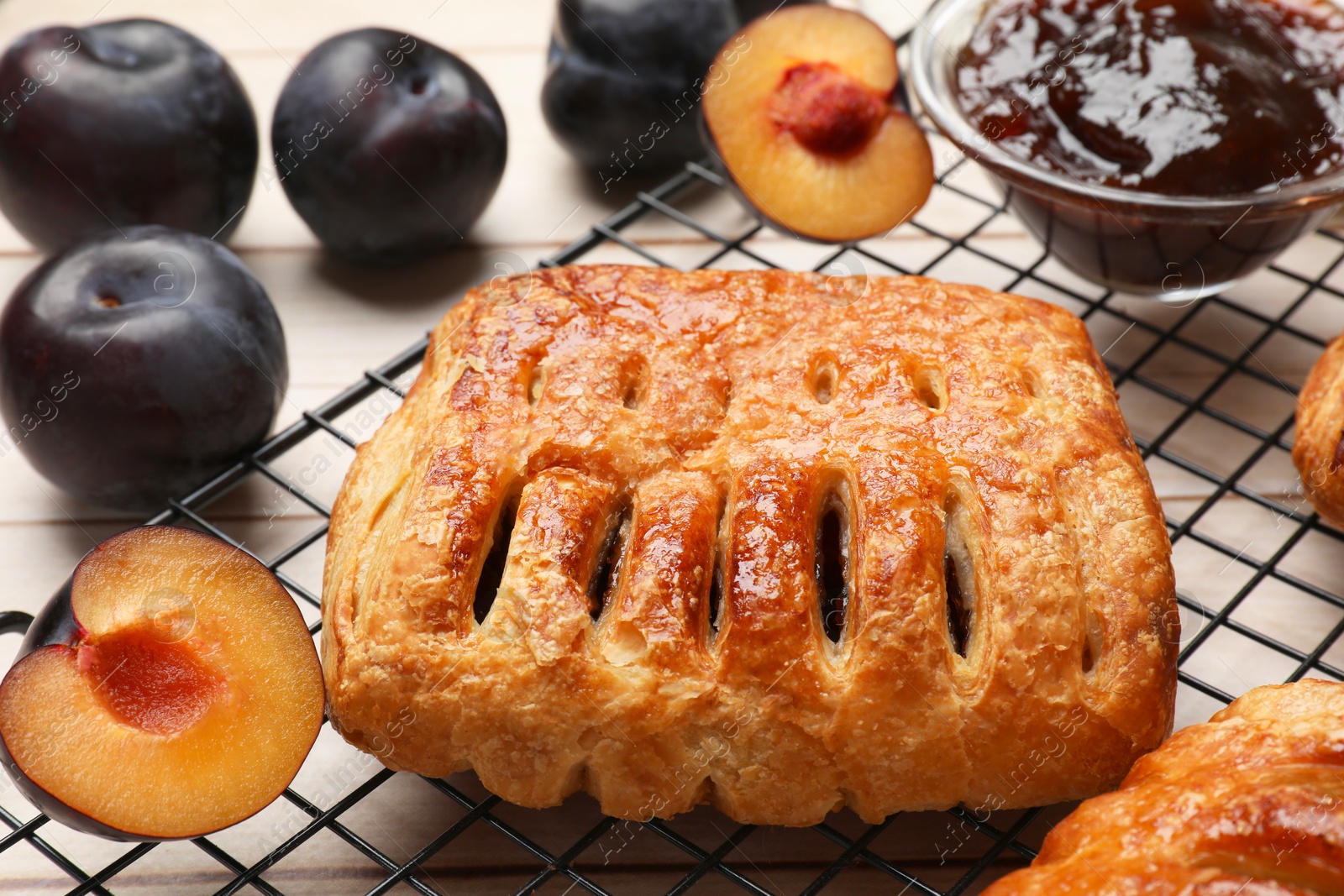 Photo of Delicious puff pastries and plums on white wooden table, closeup