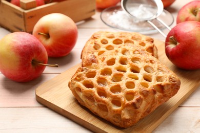 Photo of Delicious puff pastries with apples on white wooden table, closeup